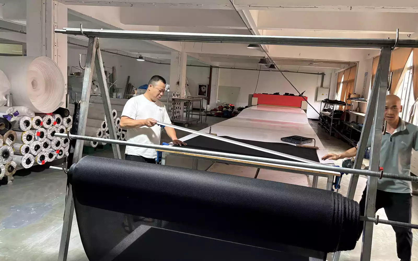 Workers spreading fabric before cutting bag panels